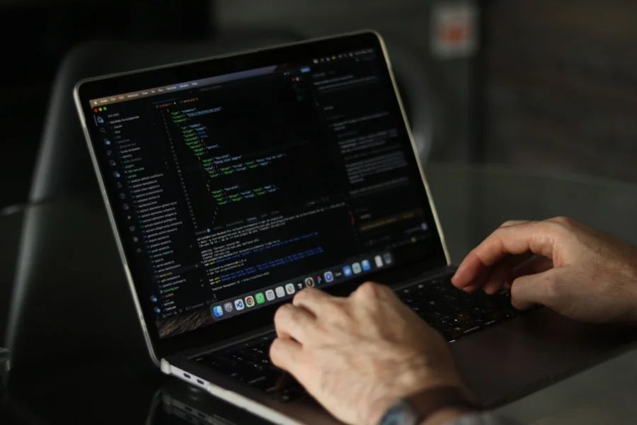 Laptop cu editorul de cod și terminalul deschise, în timpul analizei tehnice a site-ului.